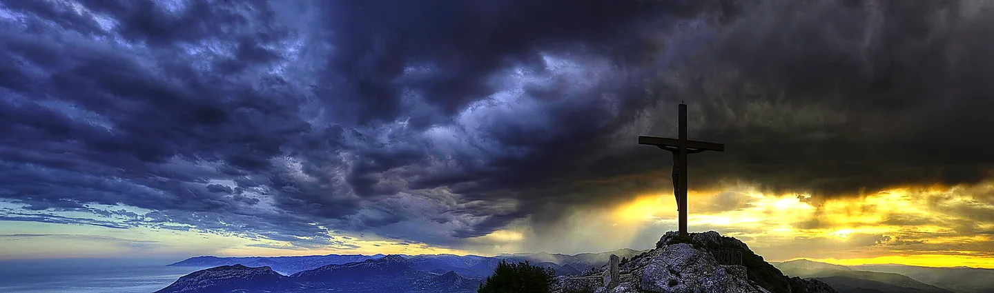 La croce sulla vetta del Monte Tuttavista a Galtellì al tramonto, con le montagne della Baronia e il mare sullo sfondo